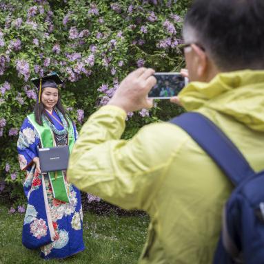 A student in a colorful graduation gown has their picture taken by their parents.